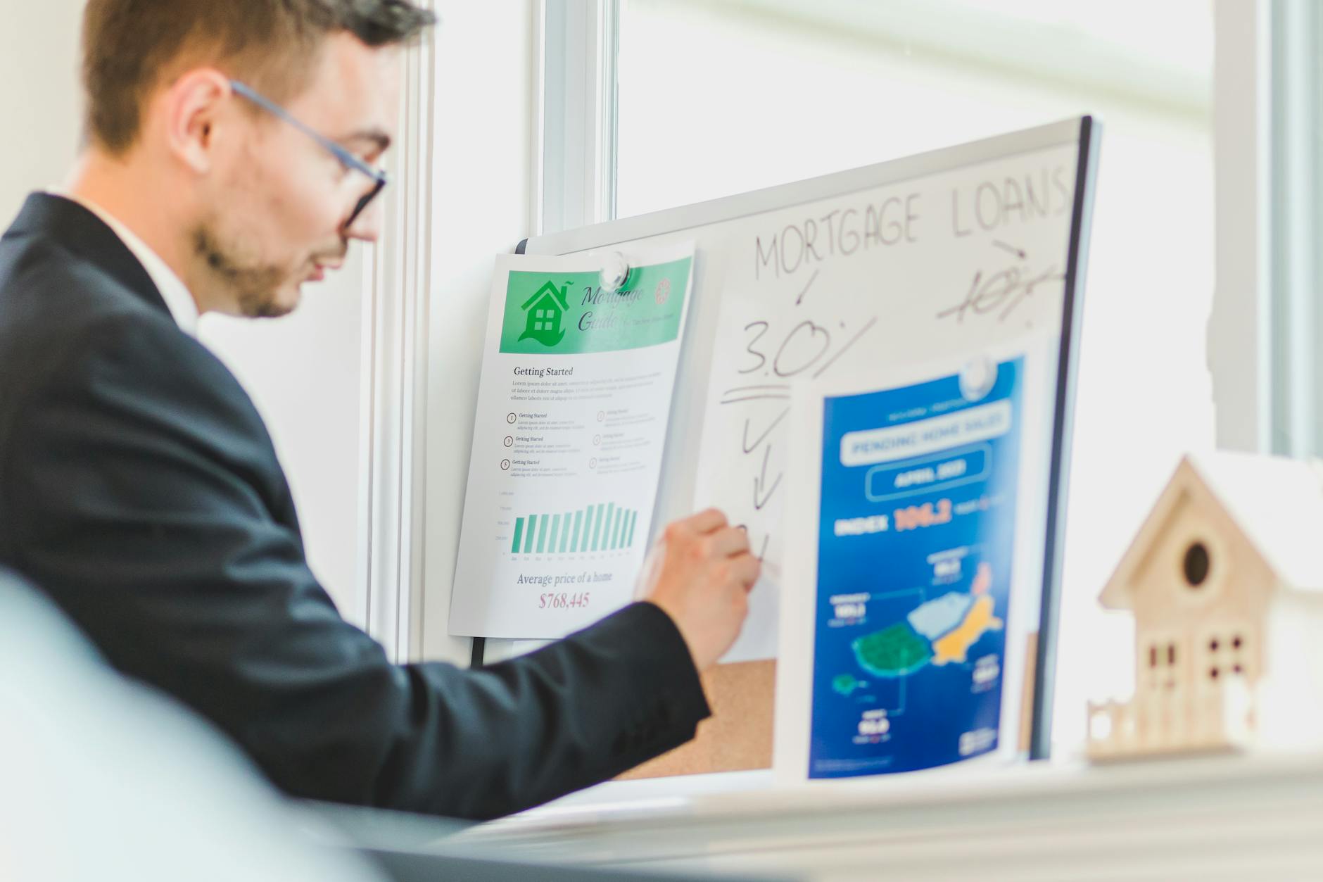 Real estate agent reviewing mortgage loan details on a whiteboard in a modern office.