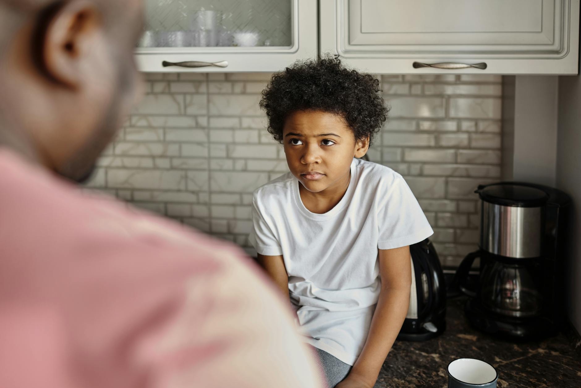 A father and son engage in a heartfelt conversation in a warm, inviting kitchen.