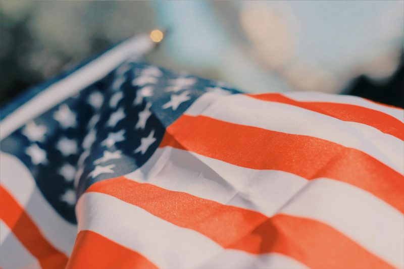 Close-up of a wavy American flag fluttering against a blurred background.