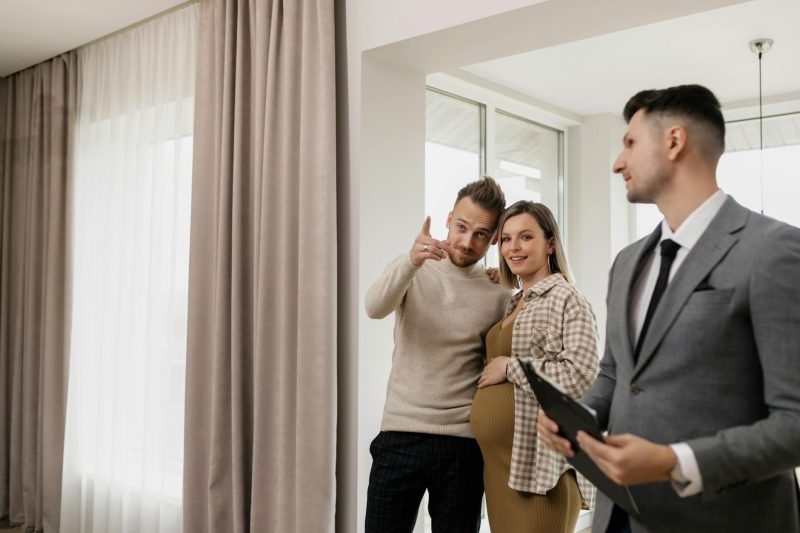 Excited couple tours a new home guided by a cheerful real estate agent.