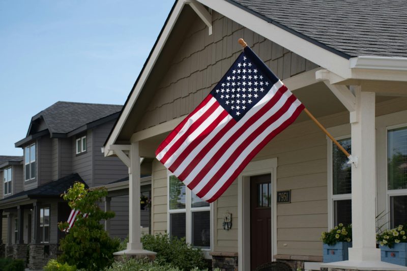 Vibrant American flag waving outside a stylish suburban house on a sunny day.