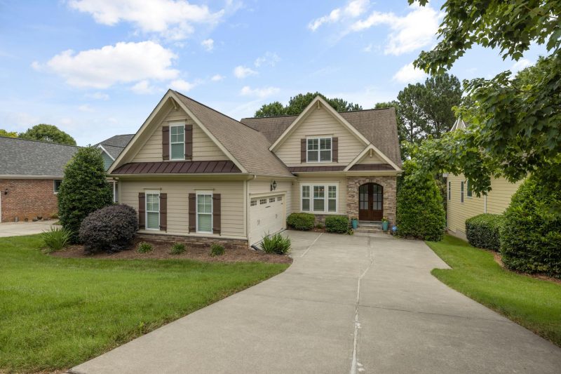 Beautiful suburban house with a well-maintained lawn and driveway under clear blue skies.