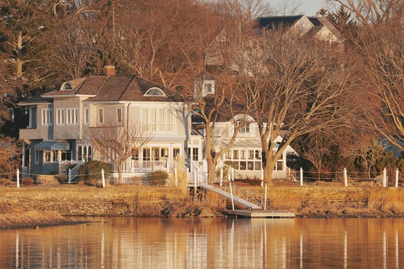 Waterfront home with serene morning light reflecting on calm water in a peaceful coastal setting.