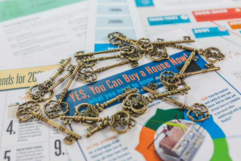 Vintage keys scattered on a real estate brochure showcasing house buying options.