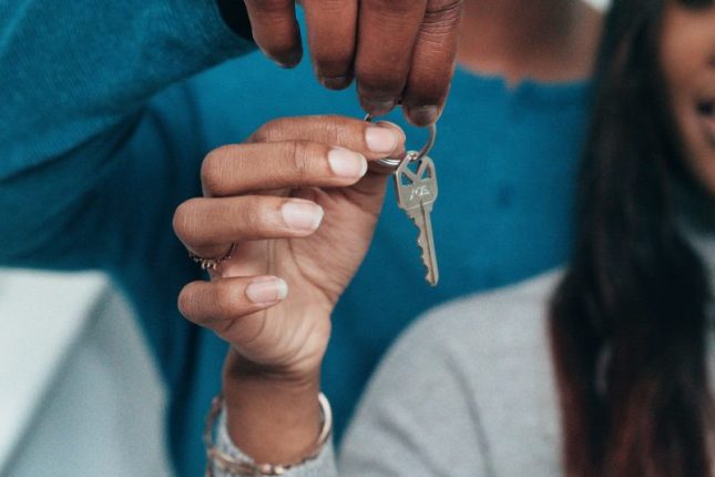 A couple joyfully holding a large key, symbolizing their new home ownership.