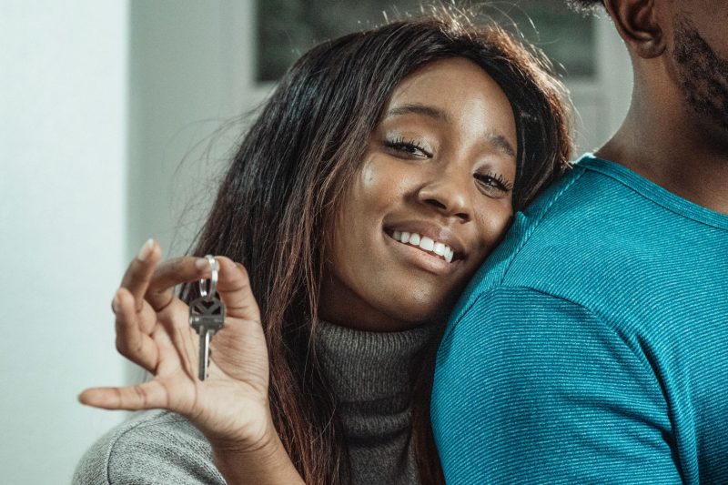 Joyful couple holding house keys, celebrating their new home purchase indoors.