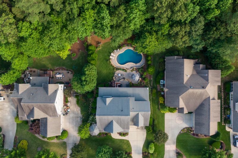 Aerial view of a lush suburban neighborhood featuring green backyards and a swimming pool.