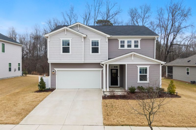 Charming two-story suburban home with a garage, surrounded by green lawns and trees in Fuquay-Varina, NC.