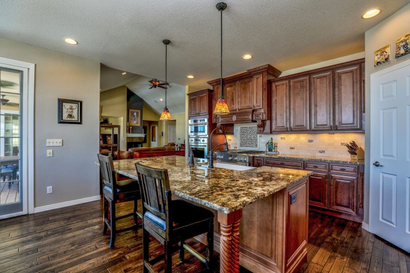 Stylish kitchen with a granite island, wooden cabinets, and modern appliances, blending rustic and contemporary design.