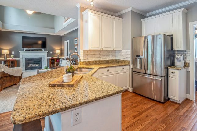 Luxurious open-concept kitchen with granite countertops and modern appliances, adjacent to a cozy living room with a fireplace.