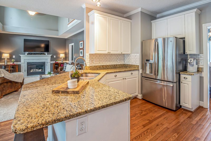 Luxurious open-concept kitchen with granite countertops and modern appliances, adjacent to a cozy living room with a fireplace.