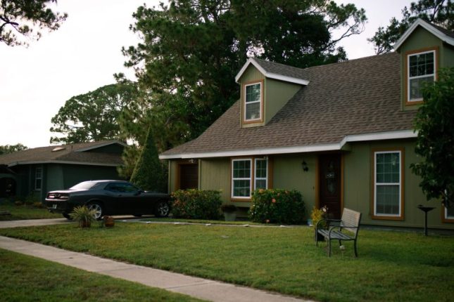 A charming suburban home with a manicured lawn and parked car, showcasing residential comfort.