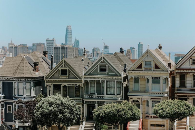 Colorful Victorian houses in San Francisco, with the city skyline rising in the background.