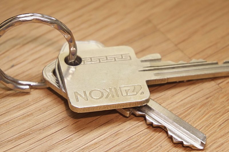 A set of metal house keys resting on a textured wooden surface.